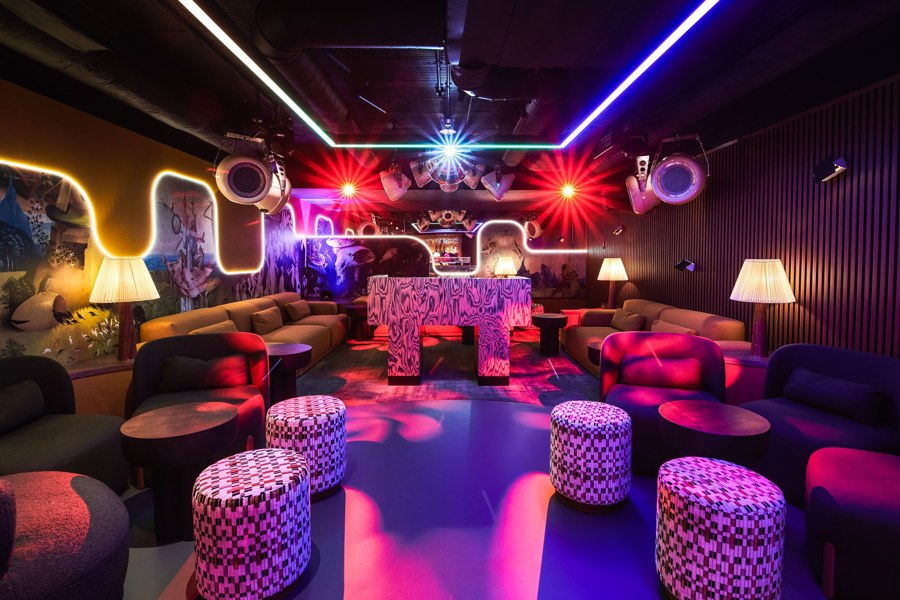Claude’s members lounge with seating and visible loudspeakers, pictured in the book.